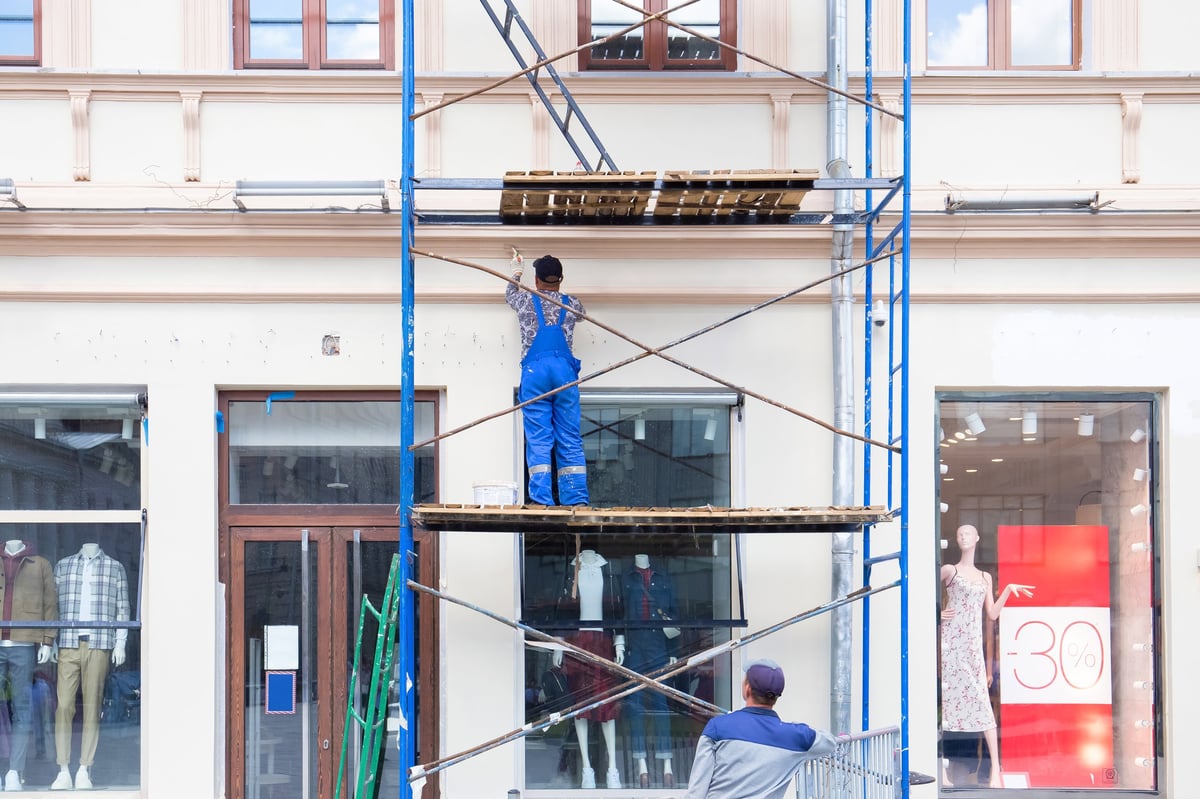 Painters painting the facade of a building on a sunny day