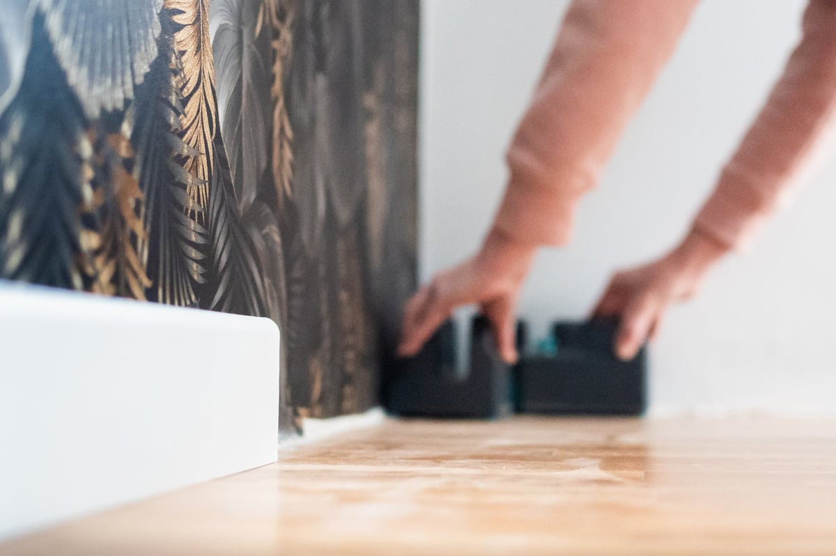 Hands carefully aligning patterned wallpaper against a wall in a home improvement project