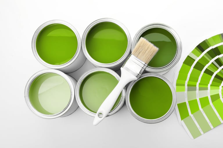 Cans with paint in shades of green, brush and color palette on white background, top view