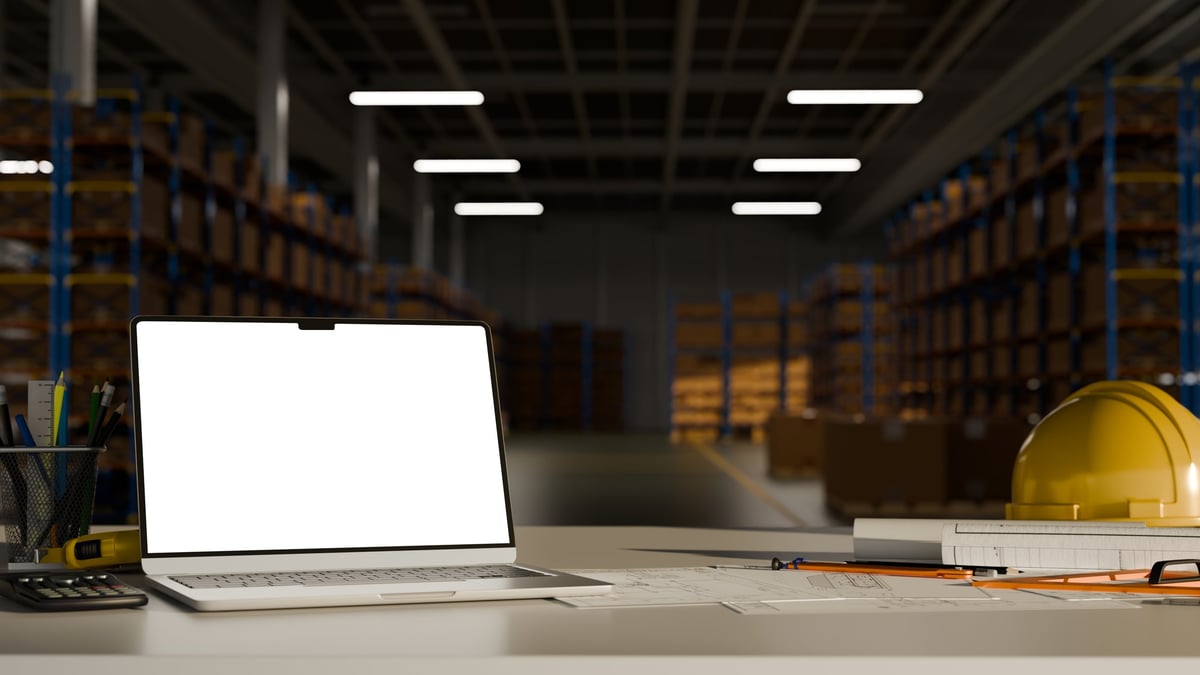 Engineering workspace with safety equipment and drafting tools inside a modern warehouse