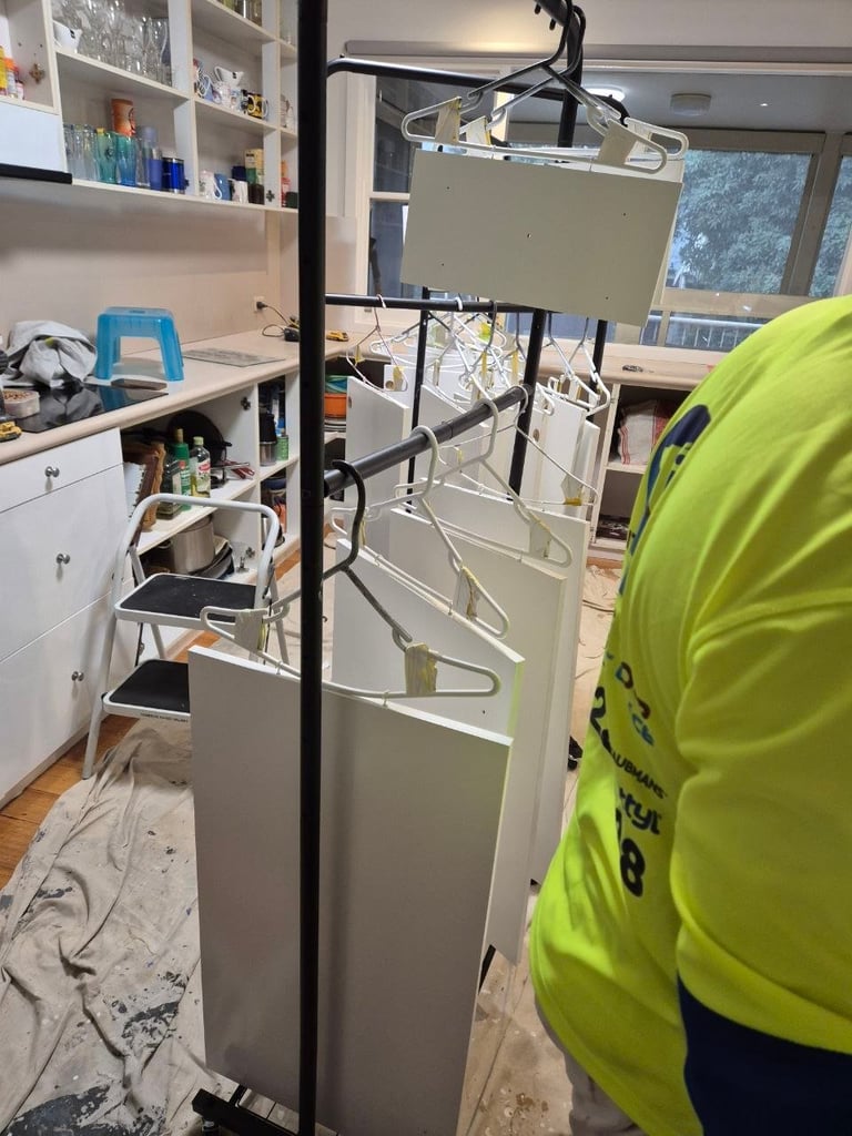 Technician in yellow vest installing or servicing a tall white air purifier or HVAC unit in a home office with shelves and desk