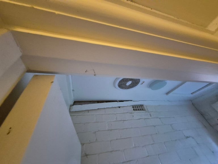 Interior view of an open refrigerator showing the top shelf, ceiling, and interior walls with freezer compartment visible