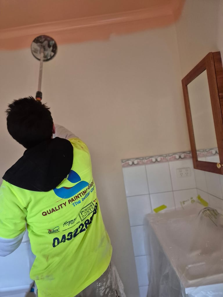 Worker in neon yellow safety vest examining bathroom ceiling fixture during renovation or inspection