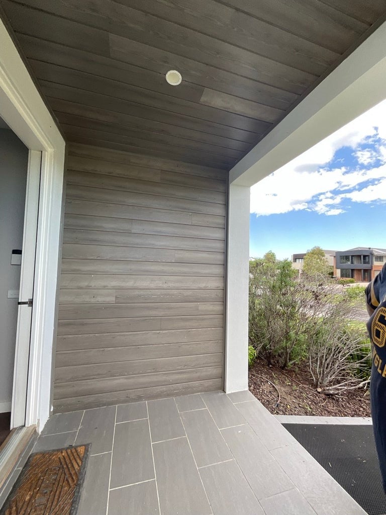 Modern entryway with dark wood ceiling, gray tile flooring, and open view of residential neighborhood with blue sky