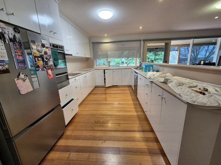 Modern kitchen with white cabinetry, marble countertops, stainless steel appliances, and wood flooring