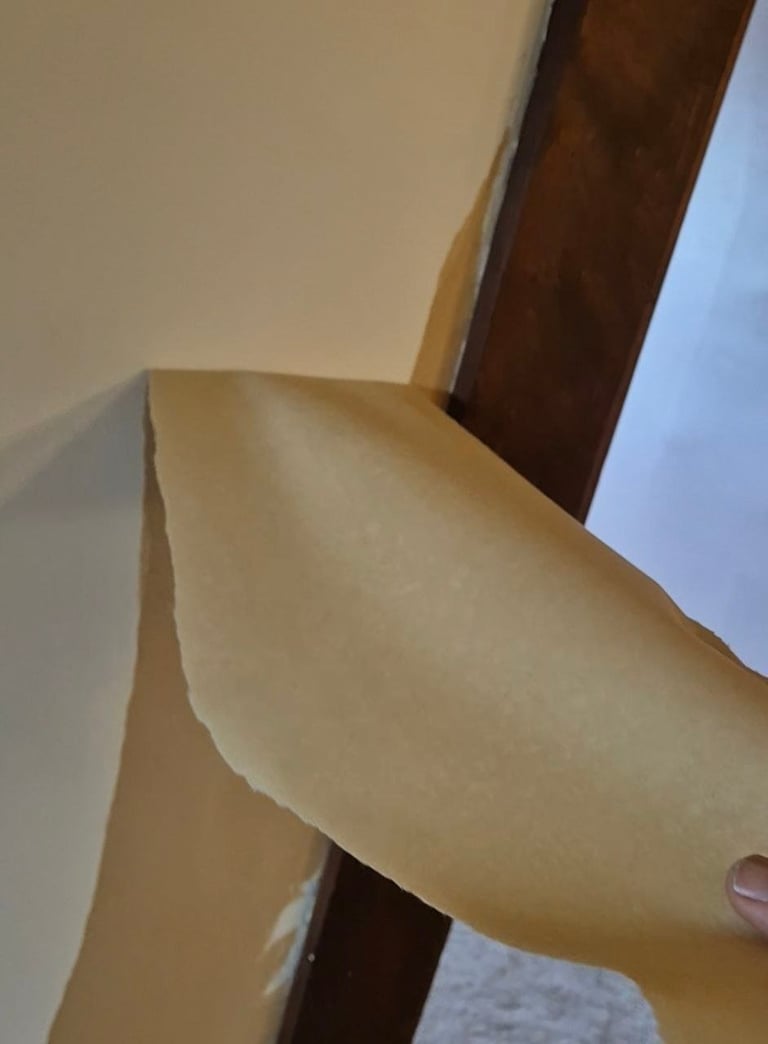 Close-up of a curved wooden chair backrest against a beige wall and dark wood frame