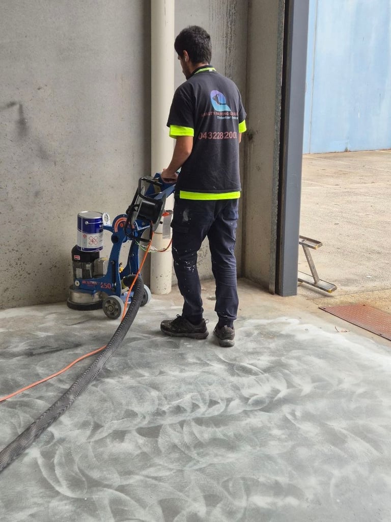 Worker in high-visibility vest operating concrete polishing machine on indoor floor surface